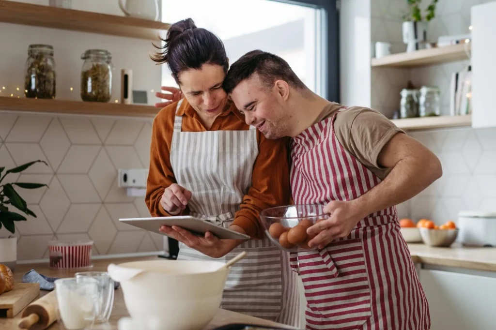 A disabled man and his support worker cooking in the kitchen